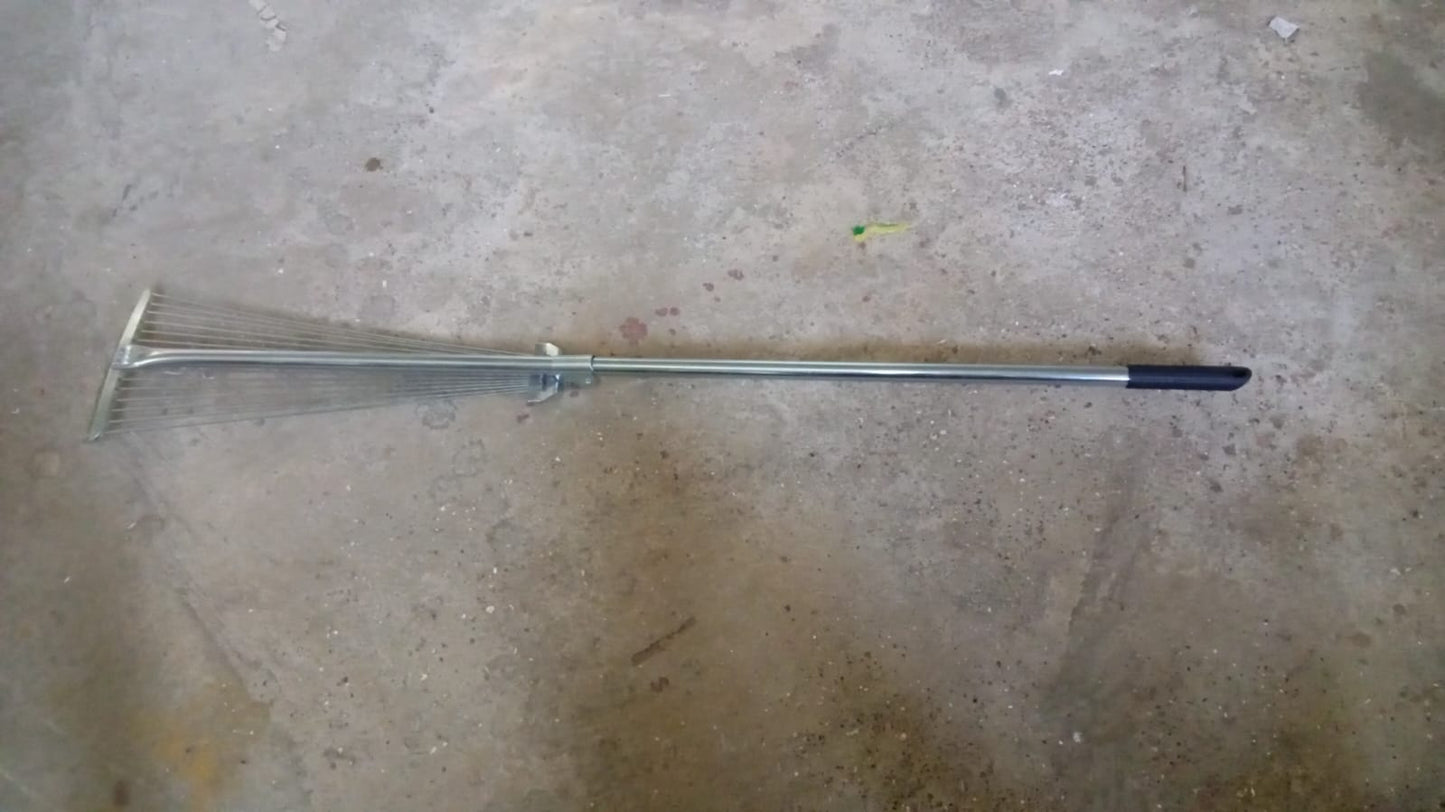 A gardener using the versatile garden rake to smooth soil in a neatly maintained yard.