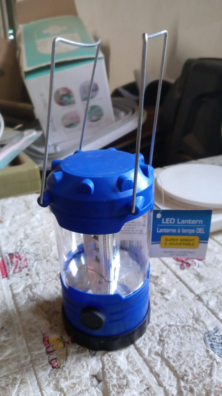 Waterproof camping lantern glowing brightly in an outdoor setting at dusk.