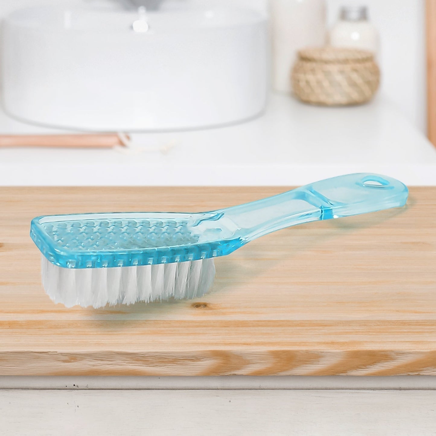 Scrubbing brush with plastic handle cleaning a pair of white shoes.