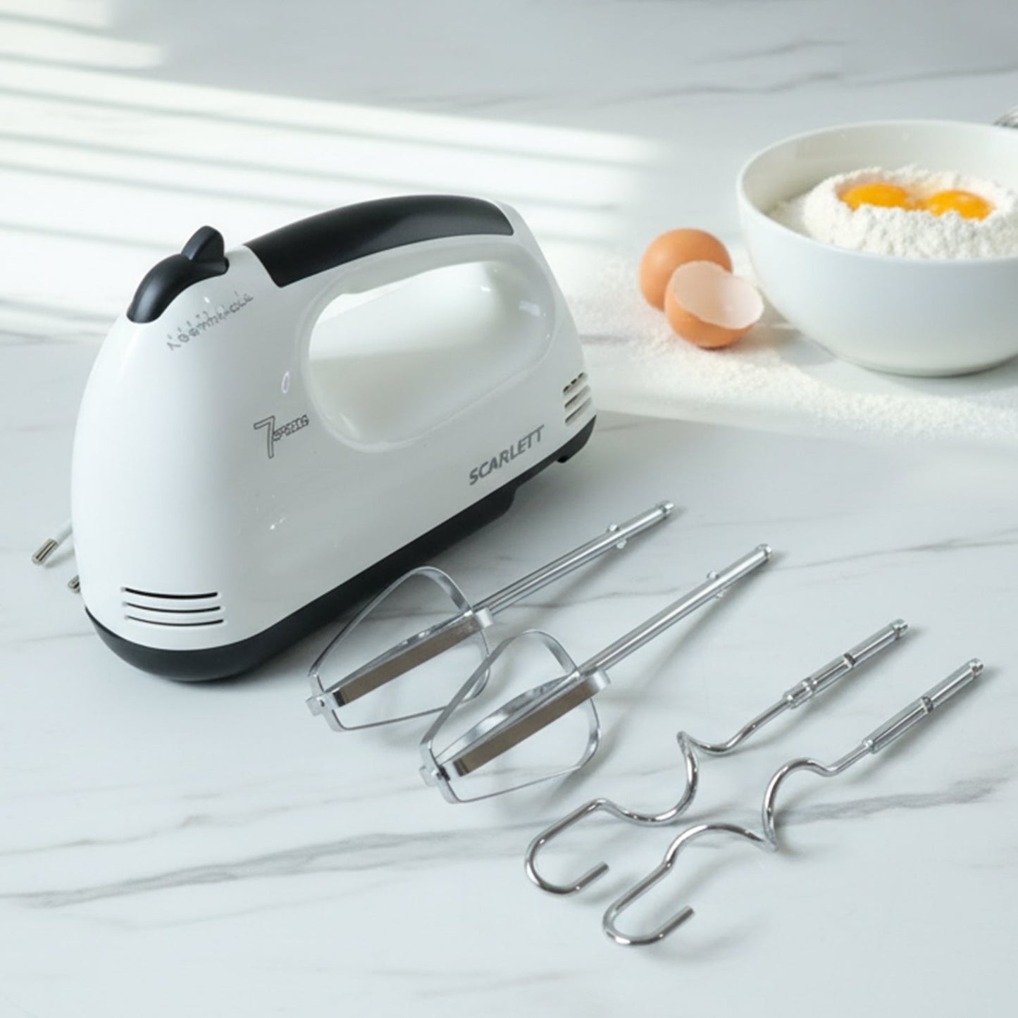 Electric hand mixer set with stainless steel beaters and dough hooks on countertop