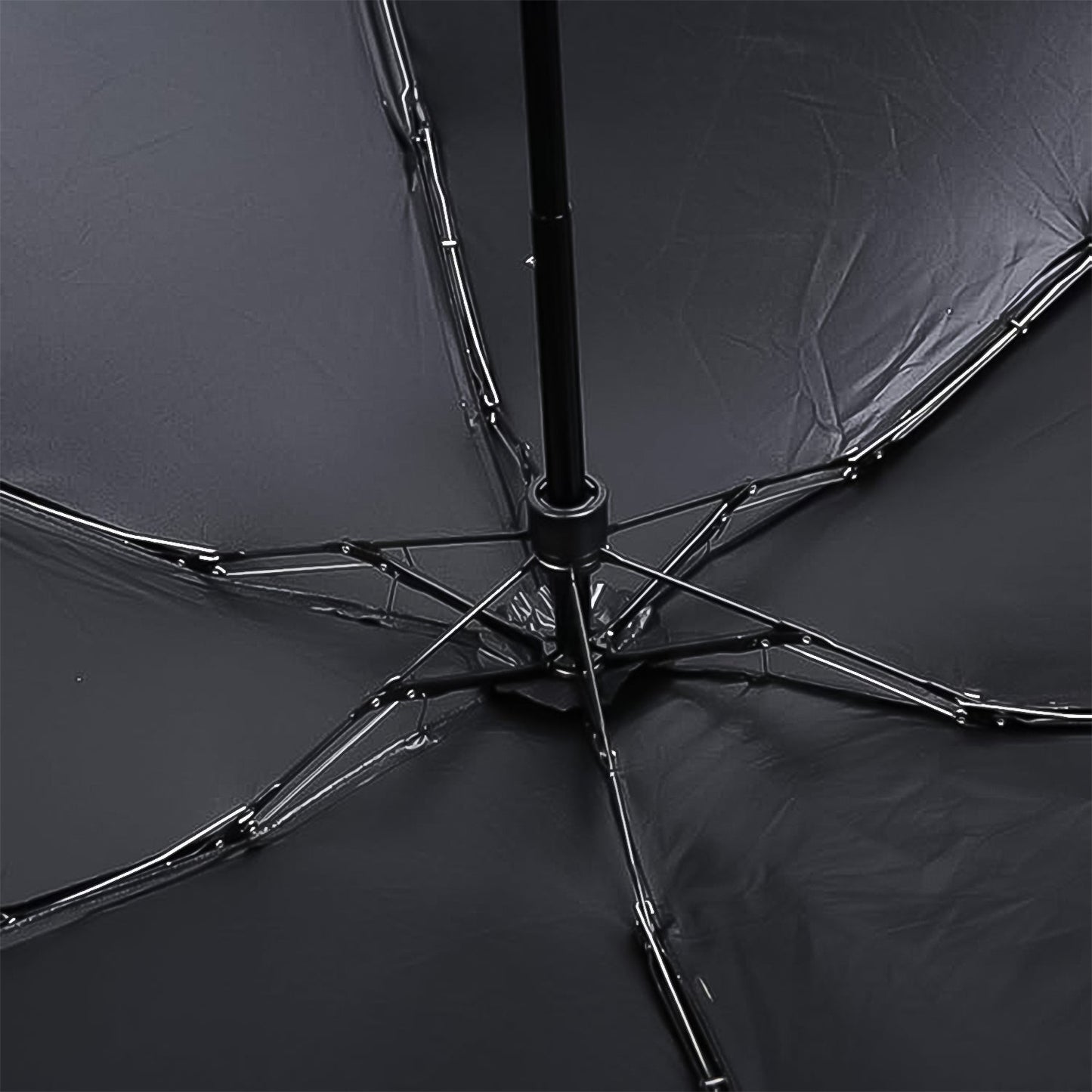 The underside of the black umbrella reveals its metal frame and ribs, supporting the dark fabric canopy.
