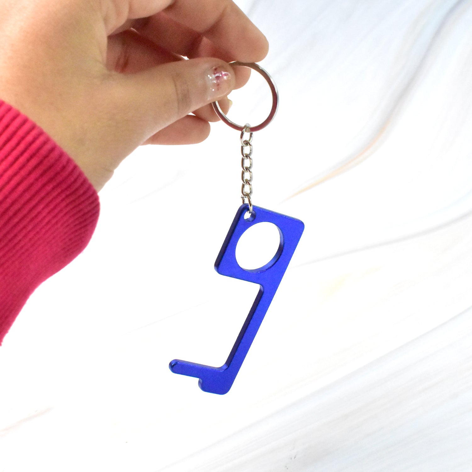 Gold-colored Safe Touch Tool keychain designed as a metal door opener on white background
