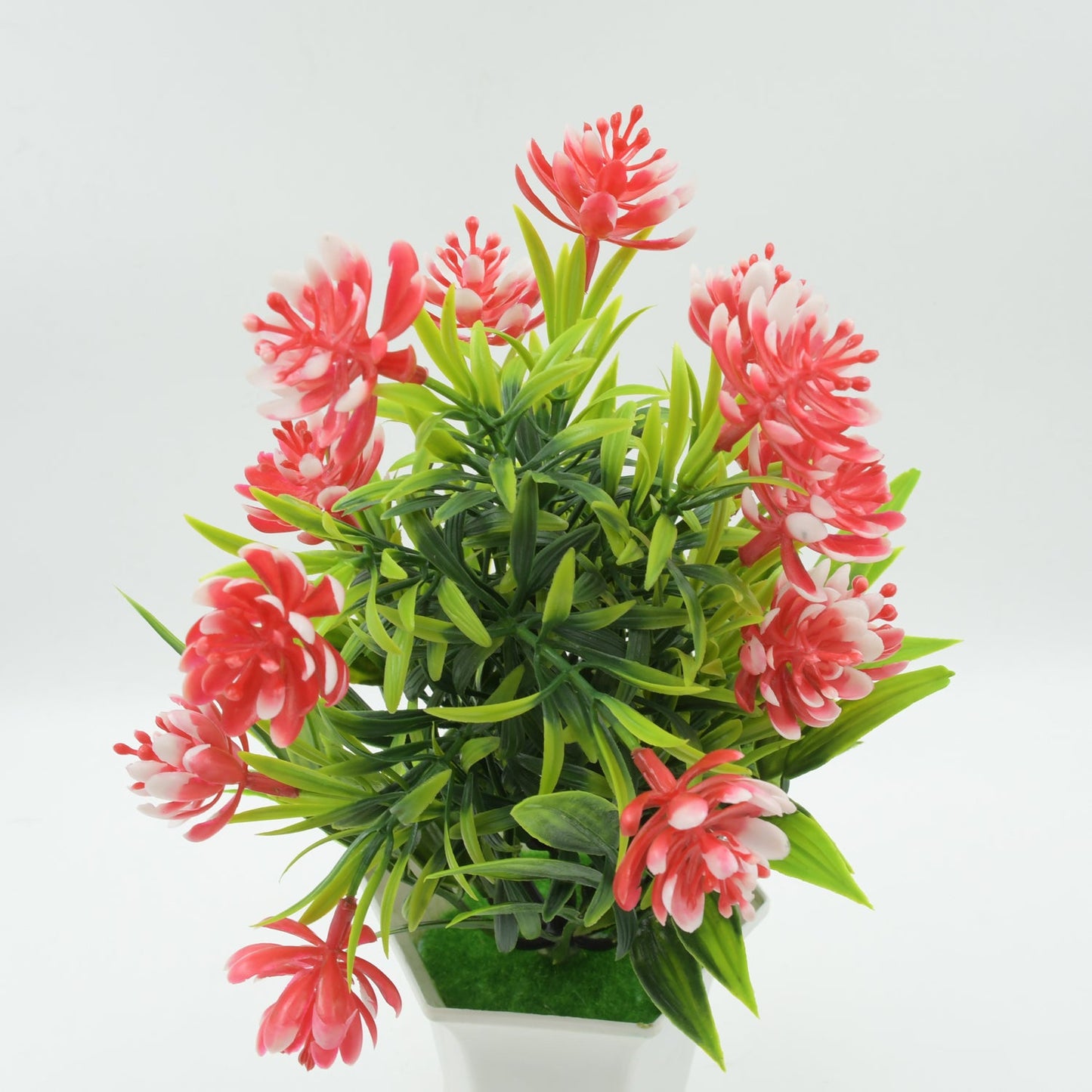 Close-up of the artificial flower plant's vibrant pink flowers and detailed green foliage.