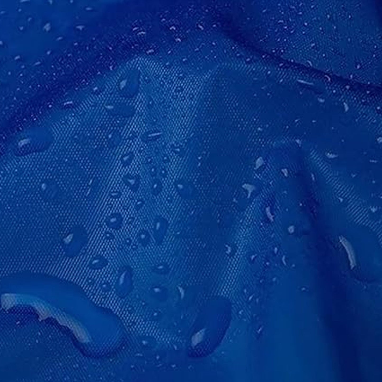 A close-up of a blue waterproof fabric with small water droplets beading on its surface.