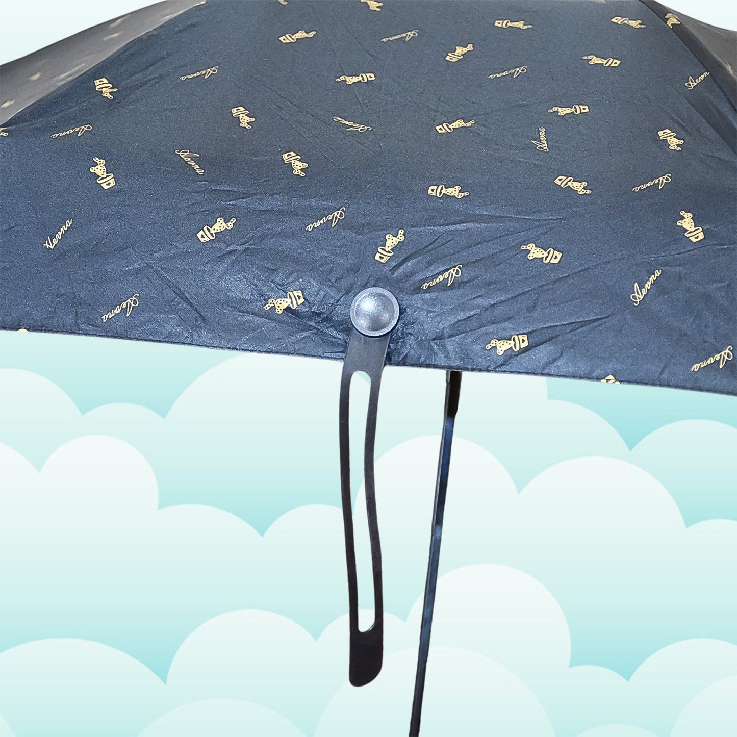 A close-up of the black umbrella canopy shows the gold musical note pattern and the handle's attachment point.