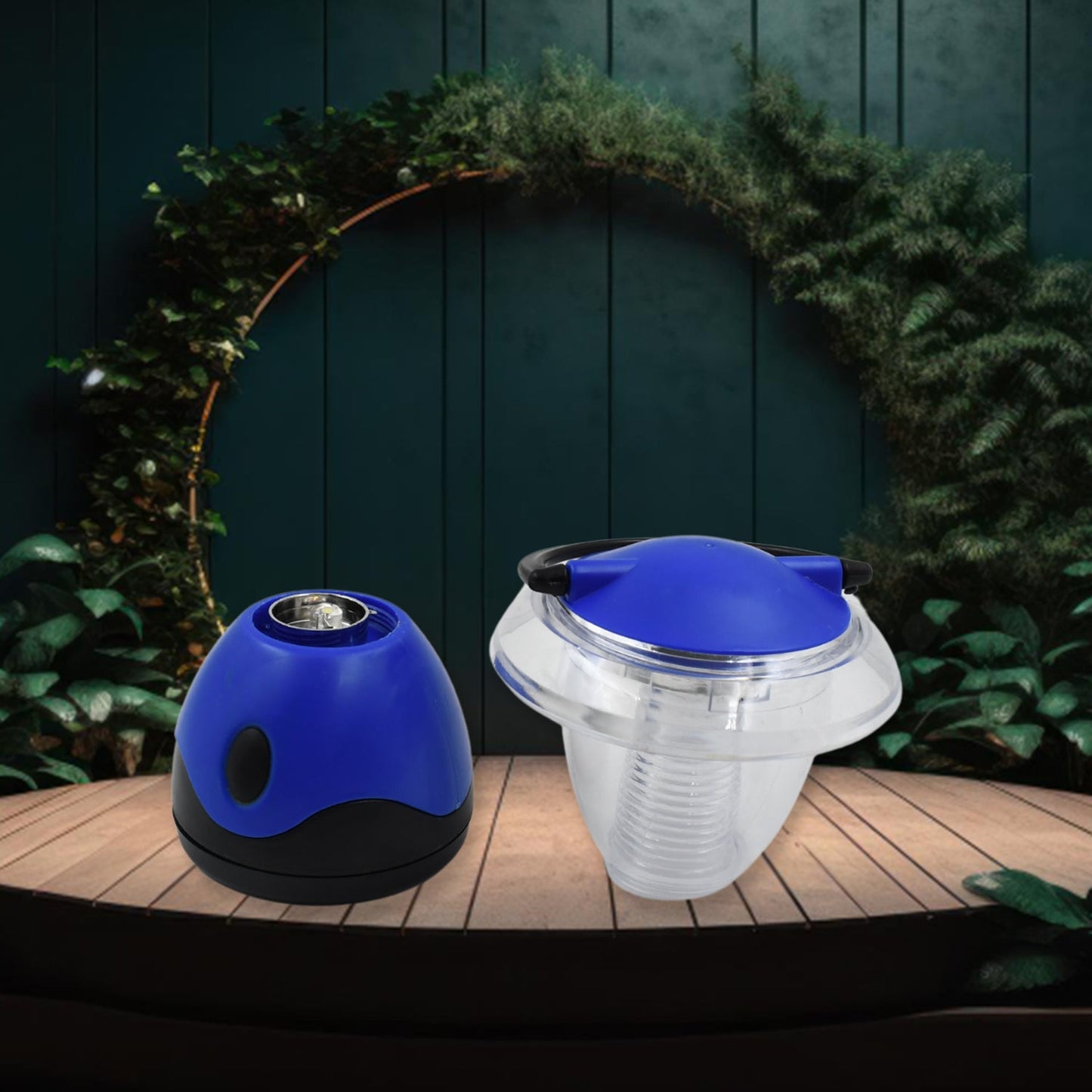 A blue and black lantern base sits next to the clear top with a blue lid on a wooden surface, against a green leafy backdrop.