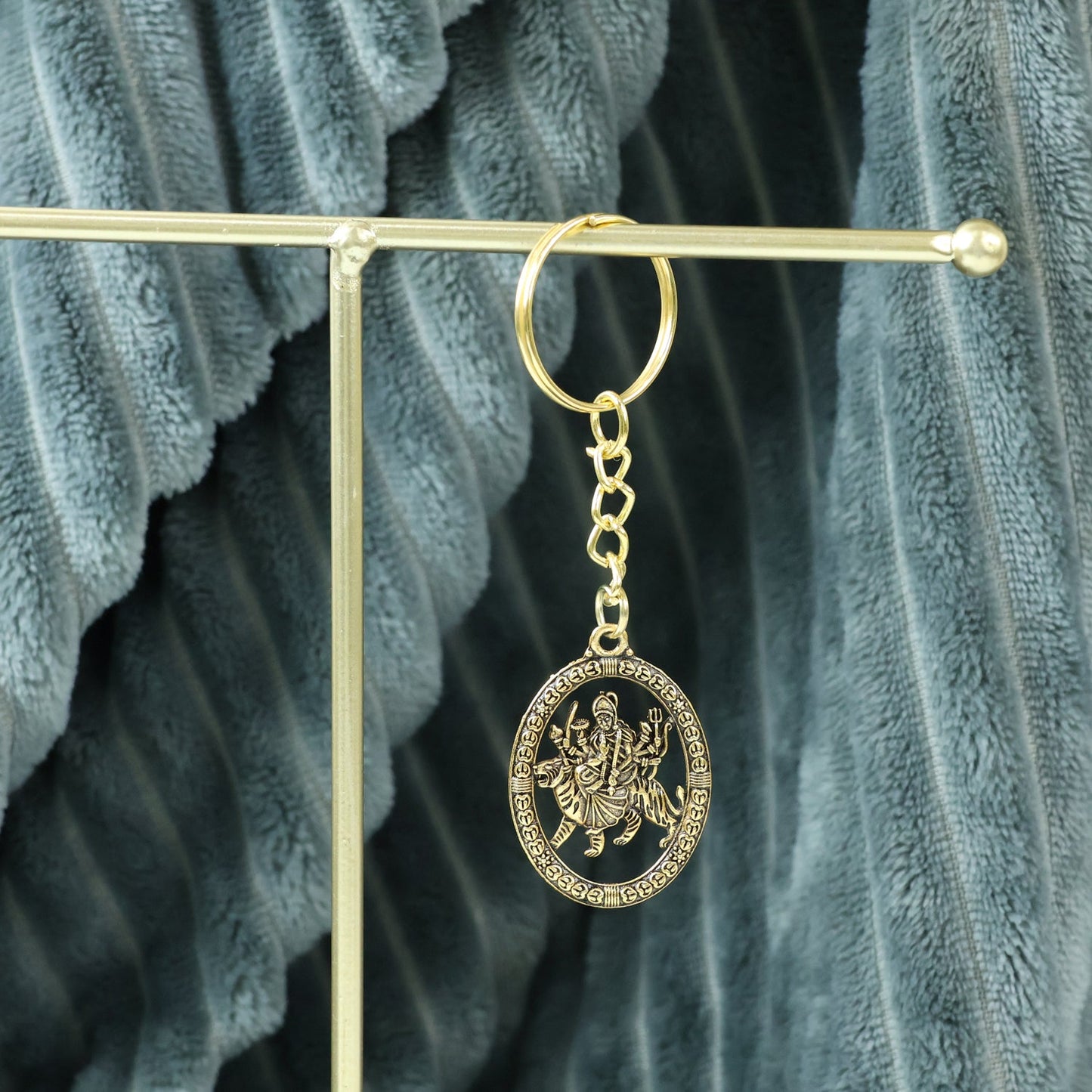 Hand holding the Maa Durga golden oval frame metal keychain