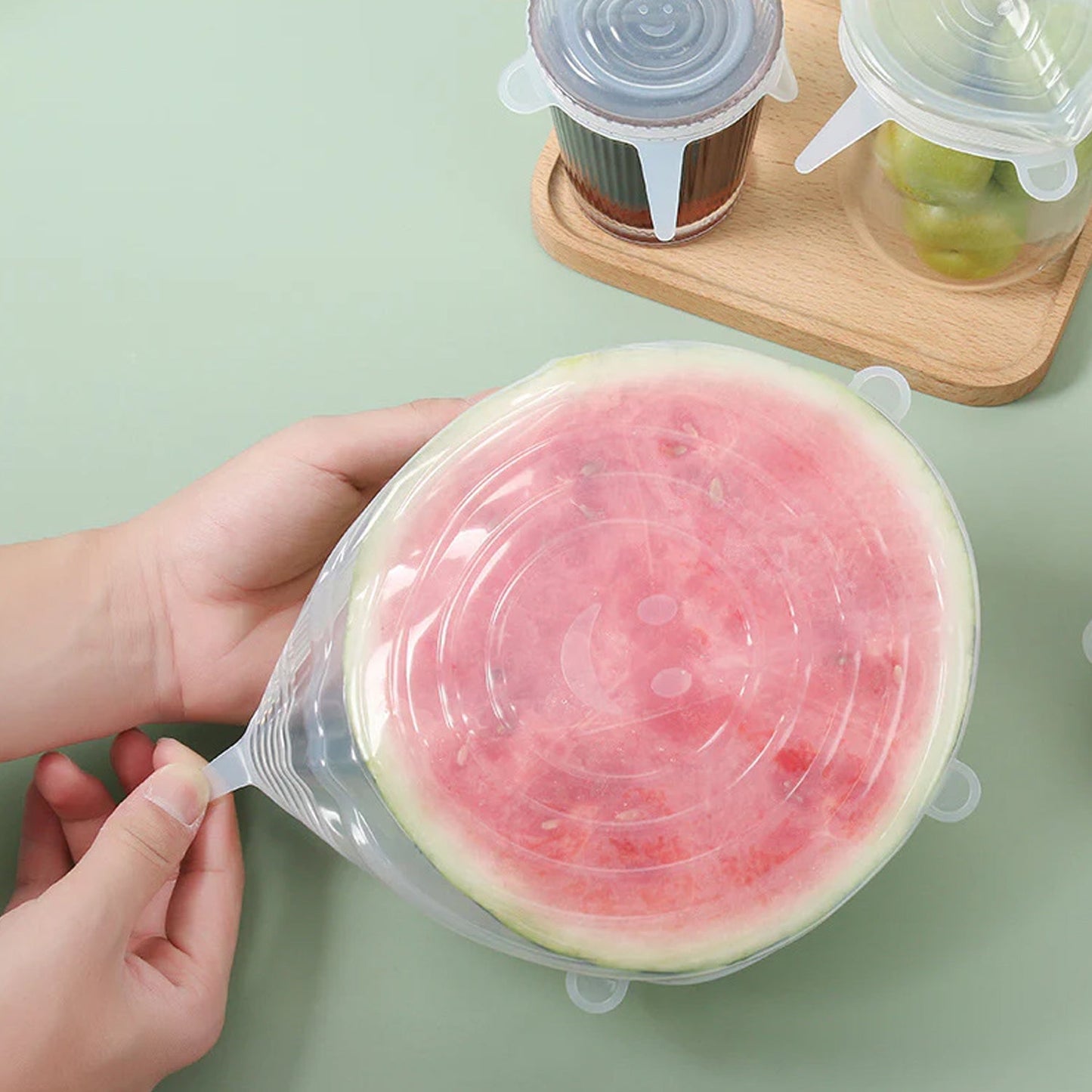 Variety of Tidy Table silicone lids stretched over different food containers and a cut fruit.
