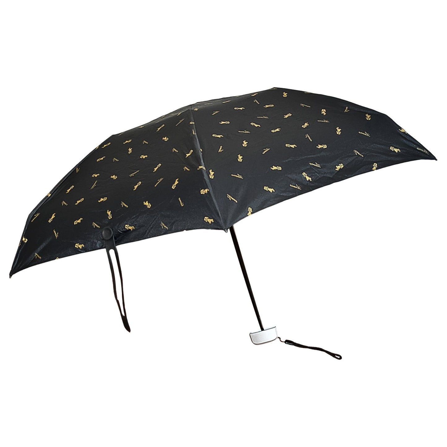 The black compact umbrella is fully open, displaying its gold musical note pattern against a white background.