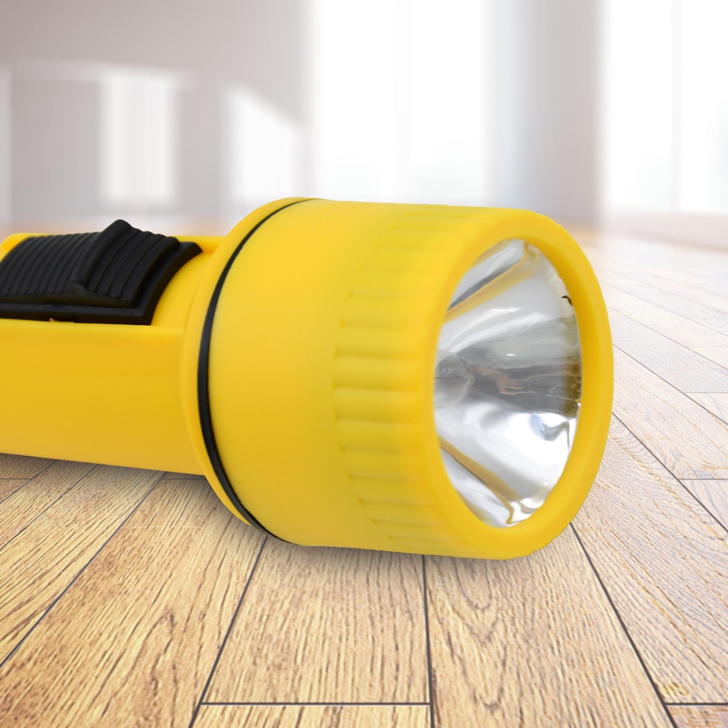 A hand holds a yellow plastic torch with a black switch and wrist strap against a sparkly blue background.