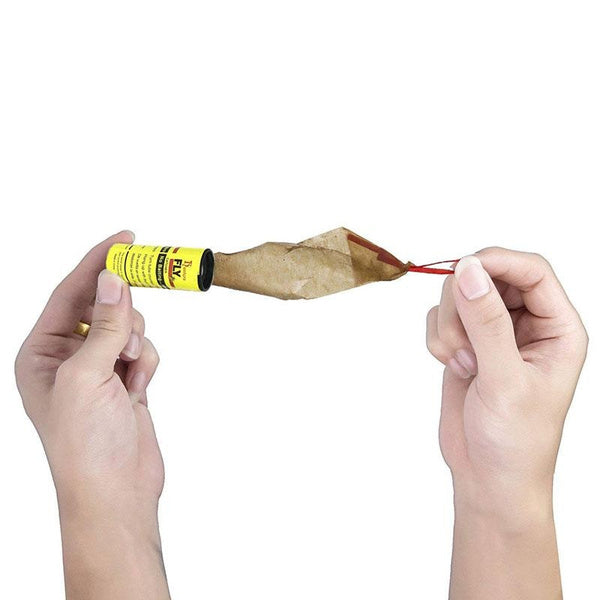 Two hands pull a brown, crinkled sticky strip from a yellow Fly Catcher tube with a red string.