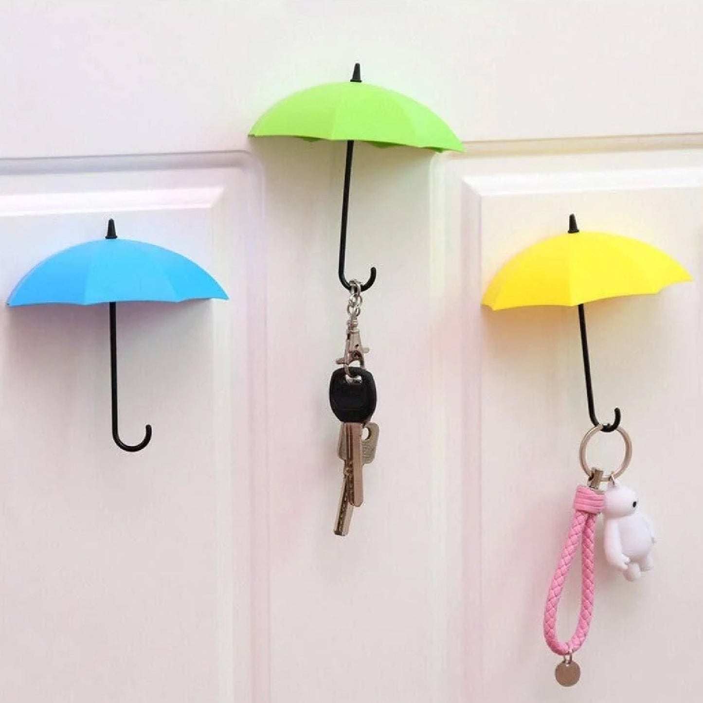 Multicolor umbrella wall hook securely holding various keys and a hat on a light surface.