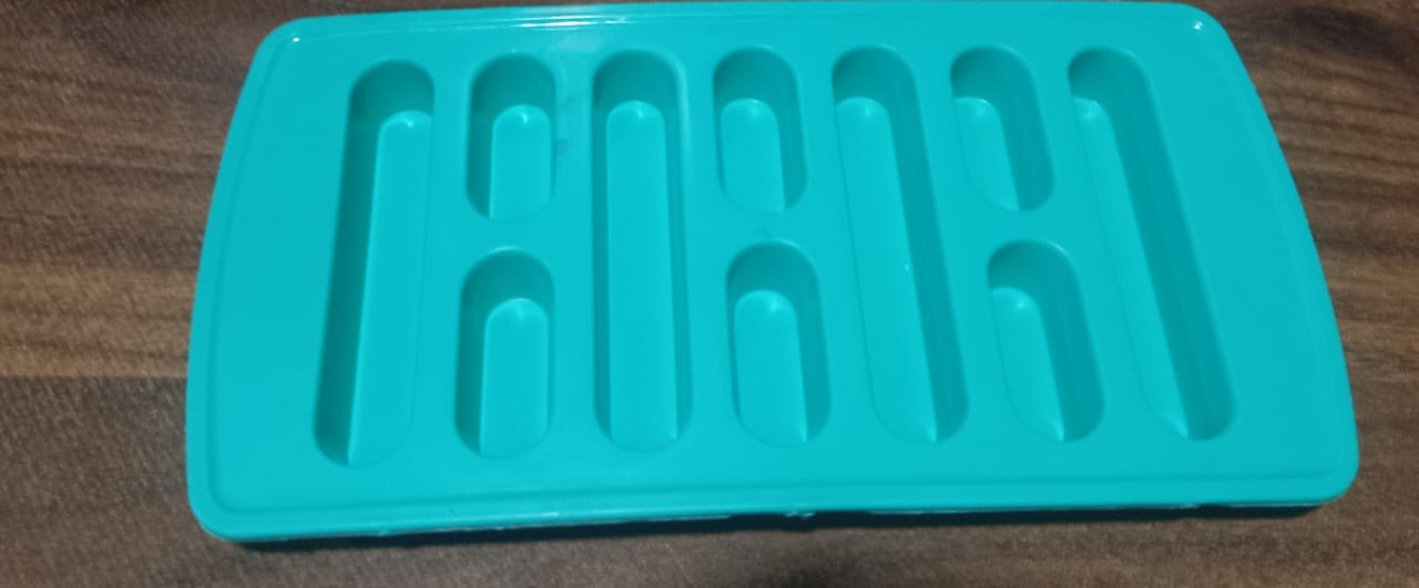 The ice tray placed next to a glass of water with ice, highlighting its practical use.