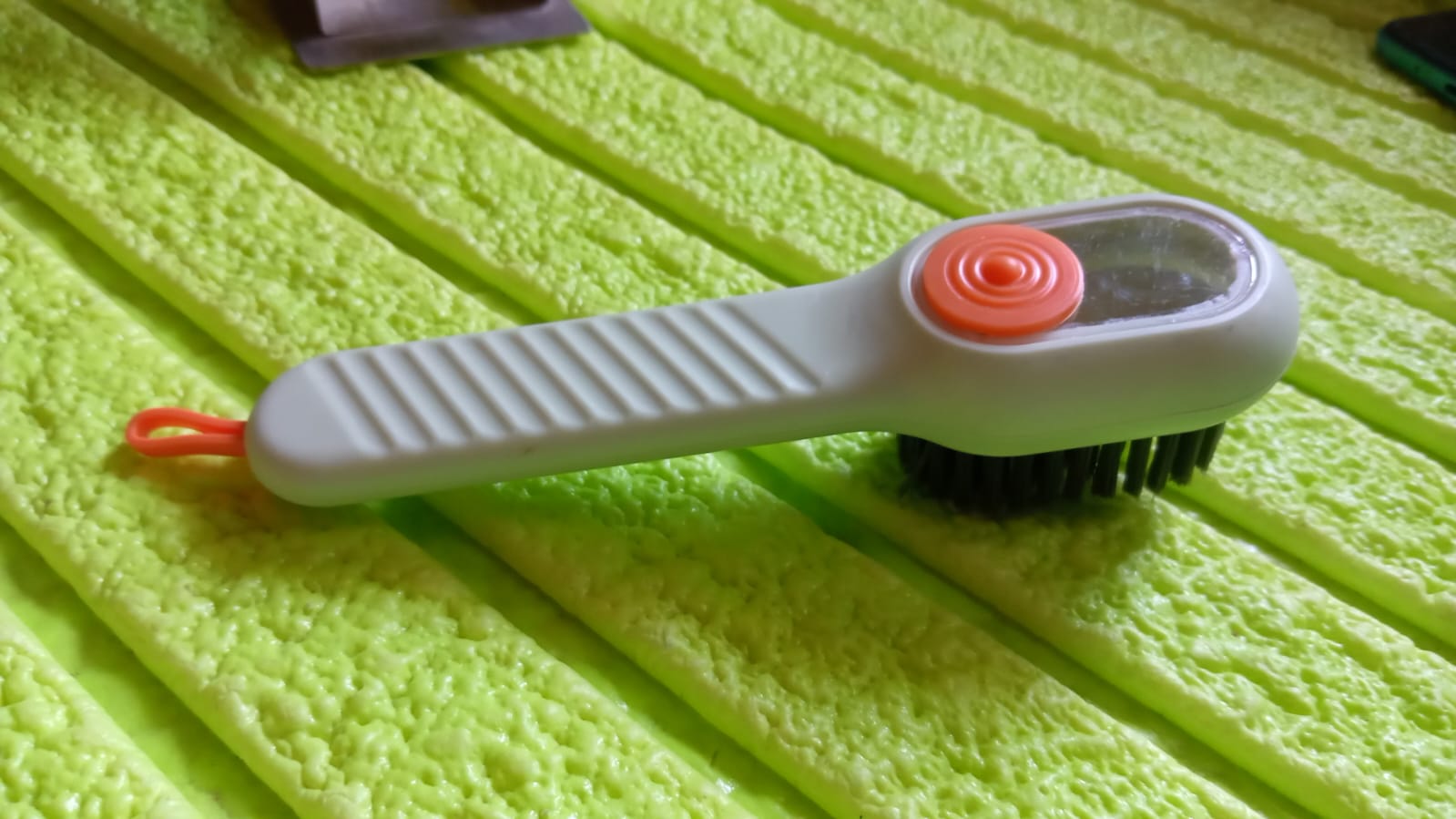 Angled view of the scrubbing brush with dispenser, highlighting its design.