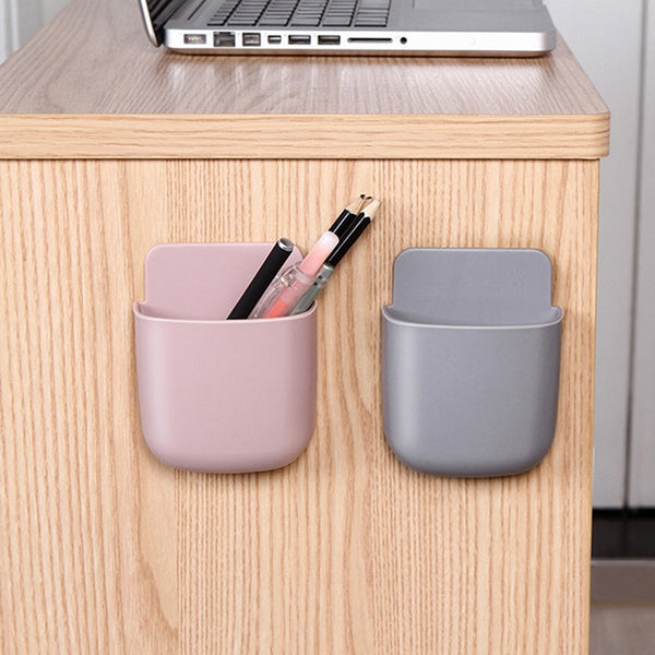 Wall mounted organizer holding a phone, remote, and pen.