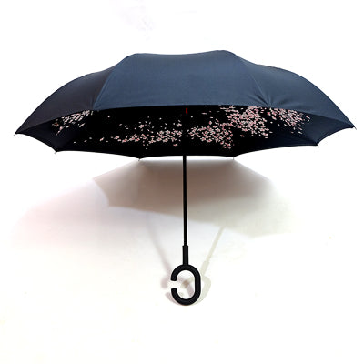 An open black reverse umbrella features a delicate pink cherry blossom pattern on its underside.
