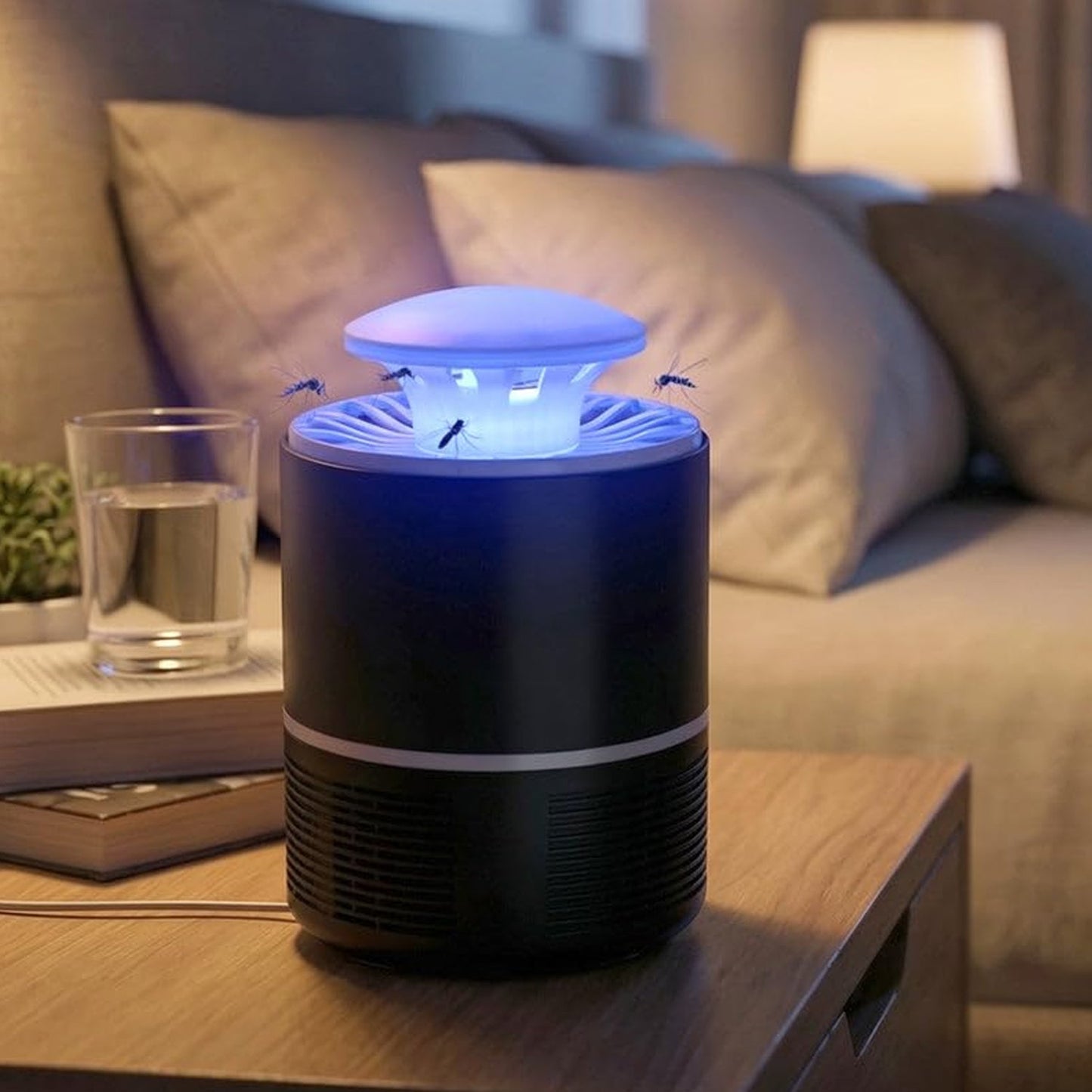 A black and white Mosquito Killer Lamp with a blue light on a wooden nightstand, with a glass of water and a book nearby.