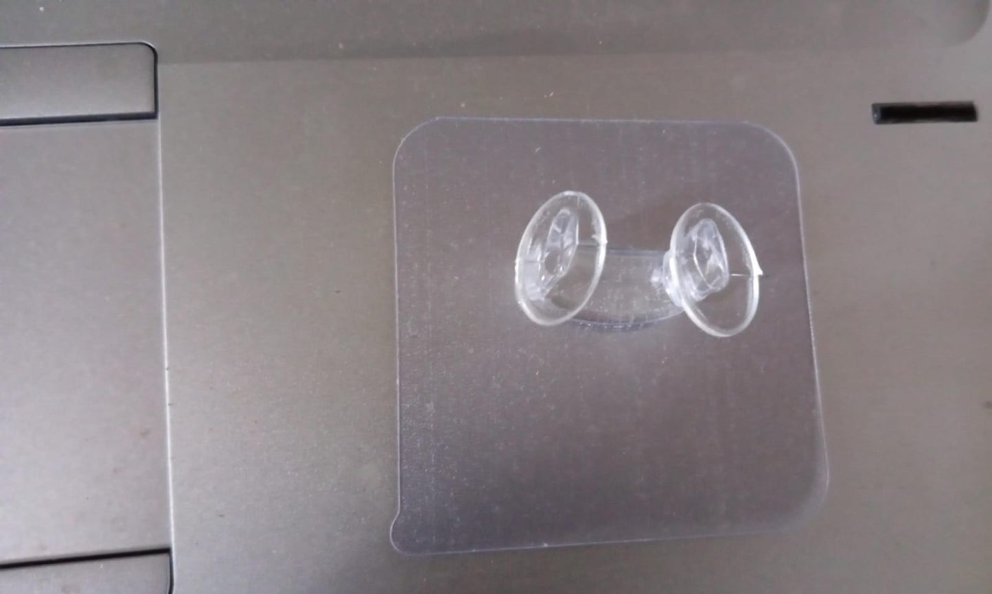 Minimalist transparent self-adhesive wall hook installed on a white wall.