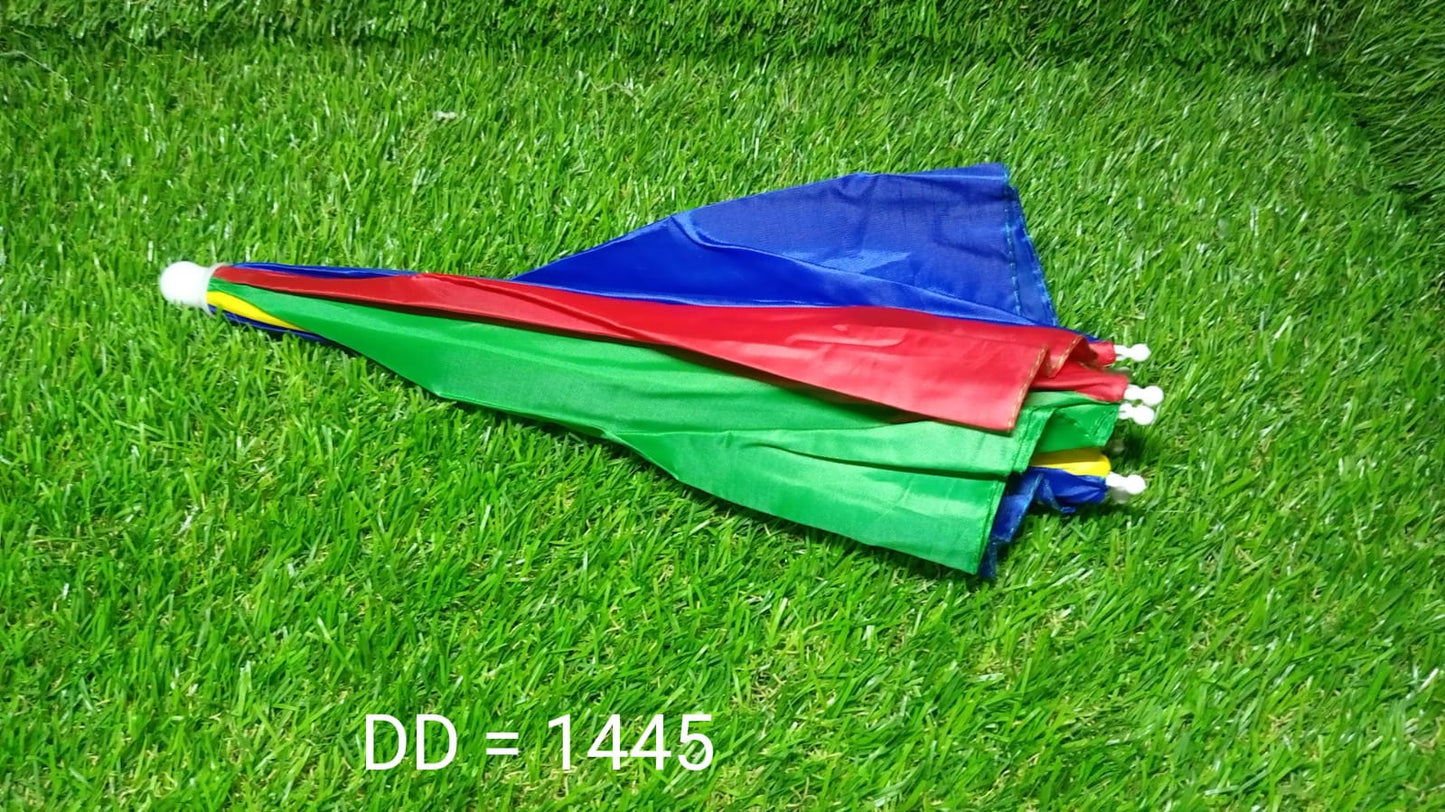 A folded, colorful red, yellow, green, and blue umbrella hat lies on vibrant green artificial grass.